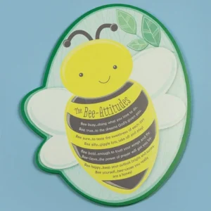 Bee-shaped MDF hanging plaque featuring colorful floral imagery and the Bee-Attitudes quote hanging on a wall.