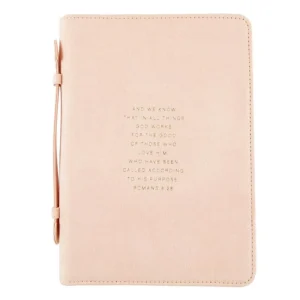 A handcrafted suede Bible cover from the Simply Faith collection, featuring Romans 8:28 in elegant gold foil lettering on the front. This durable Bible cover provides stylish protection for your scriptures.