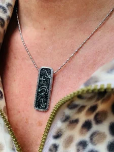 A close-up view of the Witness Collection vertical necklace featuring intricate engraved symbols, perfect for women seeking meaningful fine jewellery.
