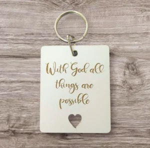 A decorative metal keyring engraved with the motivational quote With God all things are possible, supporting the Rock Foundation charity initiatives.