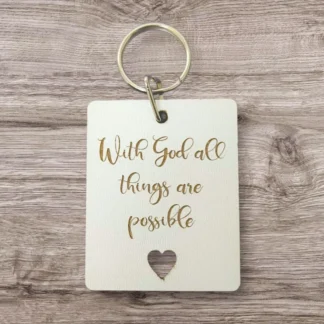 A decorative metal keyring engraved with the motivational quote With God all things are possible, supporting the Rock Foundation charity initiatives.