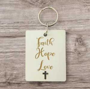 A decorative metal keyring featuring the engraved words Faith, Hope, and Love, supporting the charitable mission of Rock Foundation.