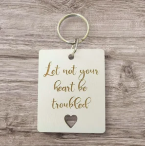 A close-up of a metal keyring featuring the inspirational quote Let not your heart be troubled, available in our collection of unique, hand-crafted keyrings for charity.