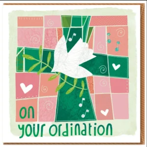 A close-up view of an elegant ordination greetings card featuring a prominent green cross design on subtly textured paper. The card is accompanied by a vibrant, colorful envelope and is presented in a clear cellophane sheath, ready for a special celebratory message.